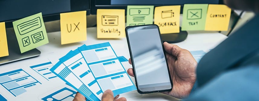Person holding mobile with sticky notes shows UX in web application development